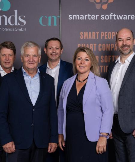 Geschäftsführungsteam vor Unternehmenslogo Geschäftsführungsteam vor Unternehmenslogo